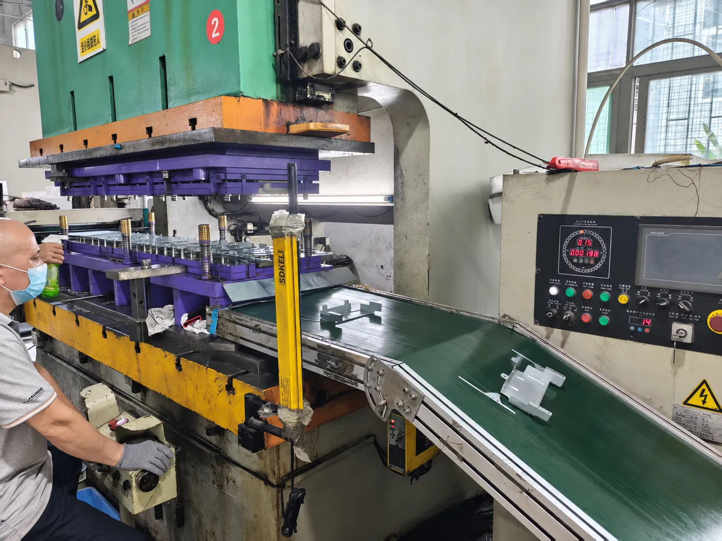 AI-retouched photo of a stamping press, open die and formed metal parts on the outfeed conveyor.